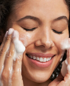 En kvinna tvättar ansiktet med Glycolic Mousse Cleanser