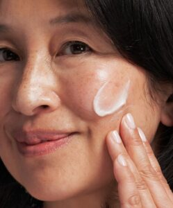 En kvinna smörjer ansiktet med Skin Brightener SPF 35