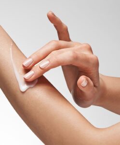 Bild på en kvinna som använder Glycolic Renewal Smoothing Lotion på sin ena arm.