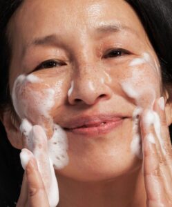 En kvinna rengör ansiktet med Exfoliating Wash