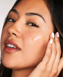 En kvinna smörjer ansiktet med Post-Acne Mark Correcting Serum